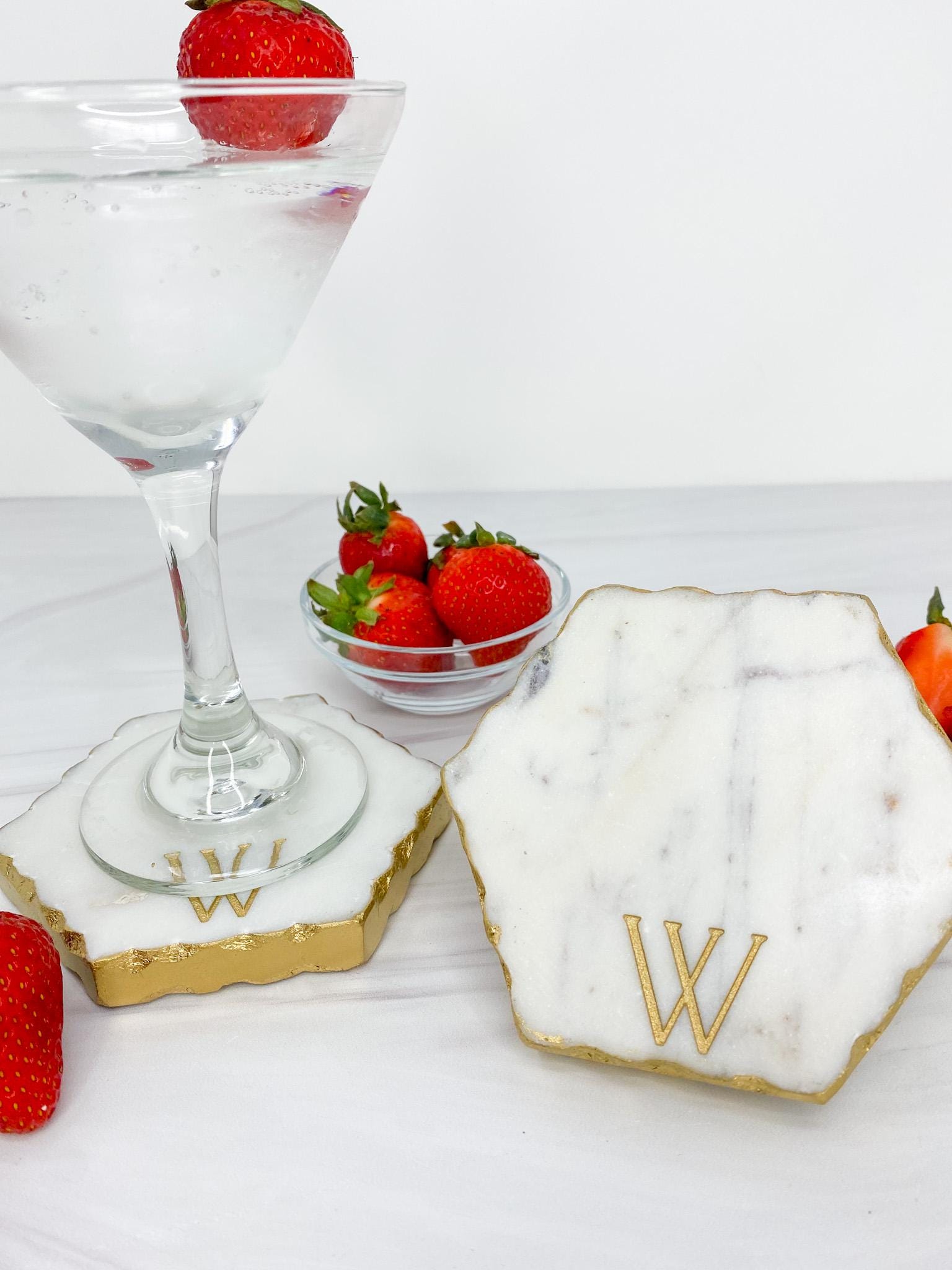 a table topped with a bowl of strawberries next to a glass of wine
