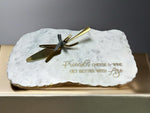 a white marble plaque with a gold knife on it